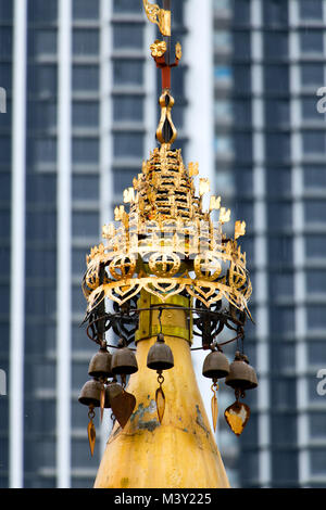 Decorative golden turret in a Buddhist monastery Dhammikarama Burmese Temple Penang, against the background of a skyscraper facade. Stock Photo