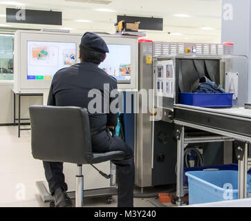 MALAYSIA, PENANG, NOV 14 2017, Checking luggage at the airport. A policeman watches a monitor baggage scanner. Stock Photo