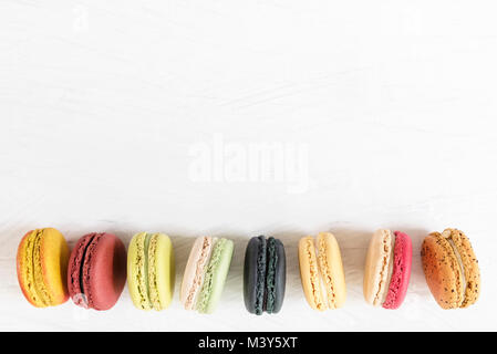Colorful macaroons in a raw on white background. Sweet desert with free copy space for text. Stock Photo