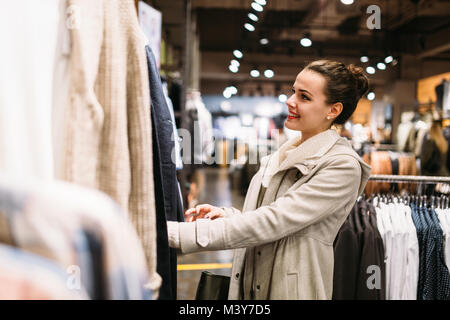 Young attractive woman buying clothes in mall