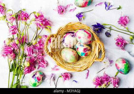 Easter eggs and colorful iris flowers on white textile background Stock Photo