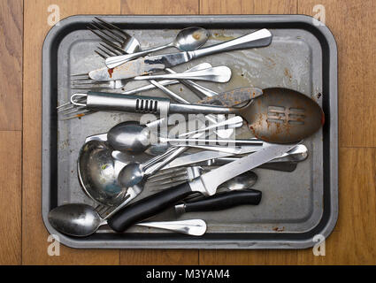Tray of dirty cutlery on a wooden background