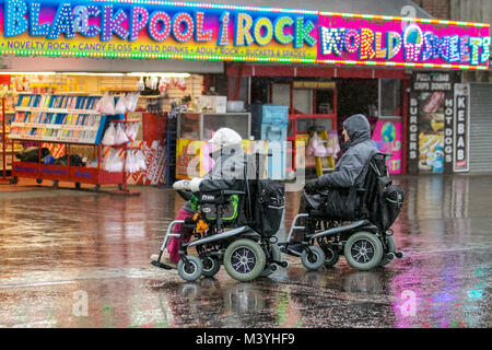 Blackpool, Lancashire. 13th Feb, 2018. UK Weather: Cold, wet and blustery start to the day on the seafront promenade Golden Mile. Normally a haven for half-term visitors this years mid-term break is without the Showzam event which used to wow the crowds in previous years. Torrential  downpours  make  it  difficult  for visitor & tourists  who  struggle  with  the  strong  gusts,  blustery  and  windy  conditions.  The  forecast  is  for  continuing  persistent  and  often  heavy  rain  slowly  moving  eastwards  with  strong  winds. Credit: MediaWorldImages/AlamyLiveNews. Stock Photo