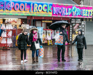 Blackpool, Lancashire. 13th Feb, 2018. UK Weather: Cold, wet and blustery start to the day on the seafront promenade Golden Mile. Normally a haven for half-term visitors this years mid-term break is without the Showzam event which used to wow the crowds in previous years. Torrential  downpours  make  it  difficult  for visitor & tourists  who  struggle  with  the  strong  gusts,  blustery  and  windy  conditions.  The  forecast  is  for  continuing  persistent  and  often  heavy  rain  slowly  moving  eastwards  with  strong  winds. Credit: MediaWorldImages/AlamyLiveNews. Stock Photo