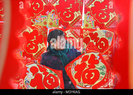 Yiyuan, China's Shandong Province. 13th Feb, 2018. A woman picks Chinese character 'Fu', which means good luck, in Lishan Street of Yiyuan County, east China's Shandong Province, Feb. 13, 2018. Different cities around China were decorated to greet the upcoming Chinese Lunar New Year. Credit: Zhao Dongshan/Xinhua/Alamy Live News Stock Photo