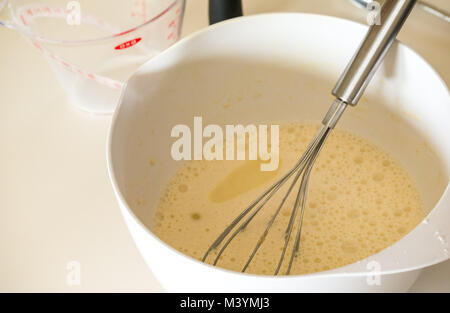 Pancake batter ready to whisk for Shrove Tuesday with flour, milk, eggs, and oil in a home kitchen Stock Photo