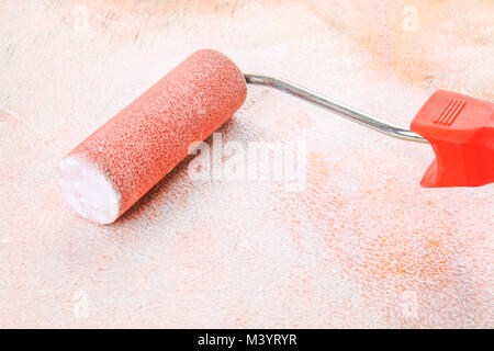 paint roll brush in white paint on plywood surface Stock Photo