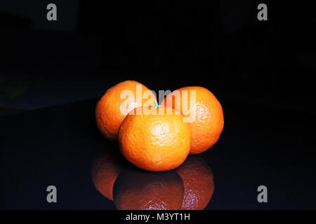 Mandarins on black reflective studio background. Isolated black shiny mirror mirrored background for every concept.. Stock Photo