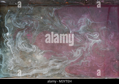 Abstract design background from a mixture of watercolor paints: the gray whirlwinds on the left break into a matte pink background. Stock Photo