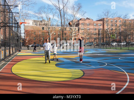 Young men playing basketball in a playground in New York's Lower East Side Stock Photo