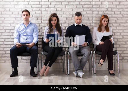 Group Of People Sitting On Chair Waiting For Job Interview In Office Stock Photo