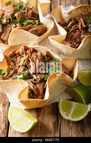 Mexican barbacoa with beef, lime and greens close-up on paper on table. vertical Stock Photo