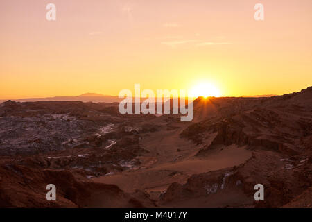 Golden sun setting in the Atacama desert behind hills and mountains. Stock Photo