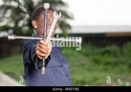 Young smiling mechanic showing her tools in her outdoor studio. Stock Photo