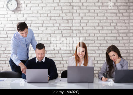 Young Happy Businessman Assisting Man In Office Stock Photo
