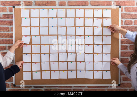 Close-up Of Business People Hands Holding Blank White Notes Notes On Corkboard Stock Photo