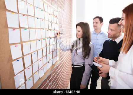 Close-up Of Business People Hands Holding Blank White Notes Notes On Corkboard Stock Photo