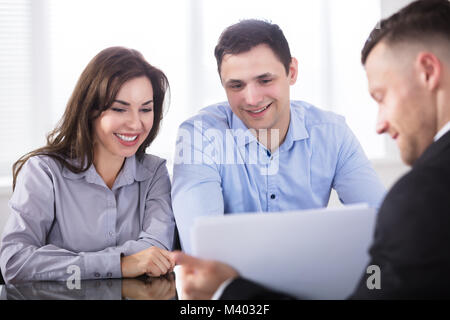 Close-up Of Advisor Showing Documents To Couple In Office Stock Photo