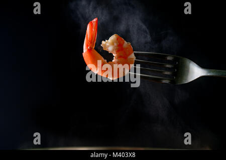 Steamed shrimp on fork isolated on dark background with copy space. Seafood buffet in restaurant concept. Use for seafood buffet promotions advertisin Stock Photo