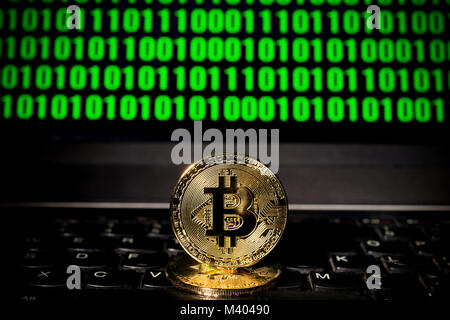 bitcoin on a laptop with a sceen of binary code Stock Photo