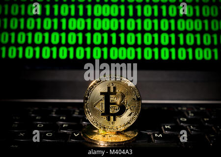bitcoin on a laptop with a sceen of binary code Stock Photo