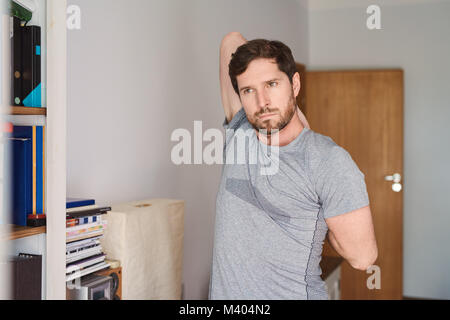 Young man in sportswear stretching before working out at home Stock Photo