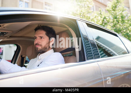 Young man driving his car through city streets Stock Photo