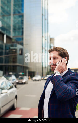 Smiling businessman standing in the city talking on his cellphone Stock Photo