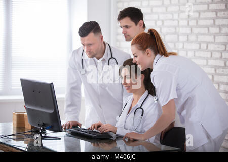 Group Of Smiling Doctors Looking At Computer In Clinic Stock Photo