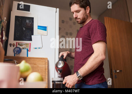 Young man preparing fresh coffee in his kitchen at home Stock Photo