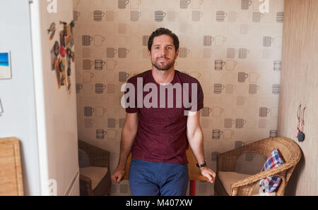 Smiling young man leaning on his kitchen table at home Stock Photo