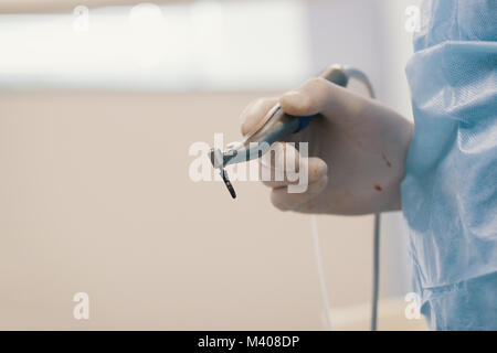 Dentist's bloody hands with drill in dental office Stock Photo
