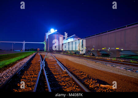 railyard and junction at night with grain elevators Stock Photo