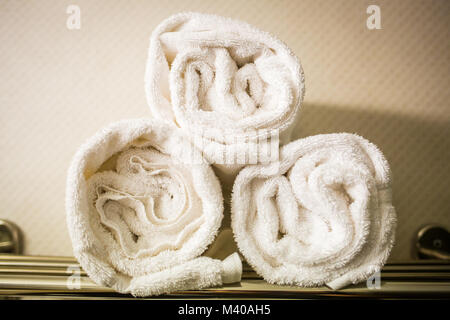 Rolled white towels on a shelf bathroom Stock Photo