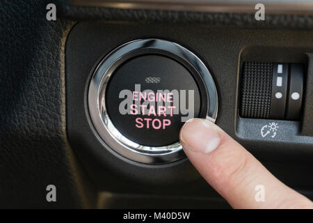 Pushing the engine start stop button of a car Stock Photo