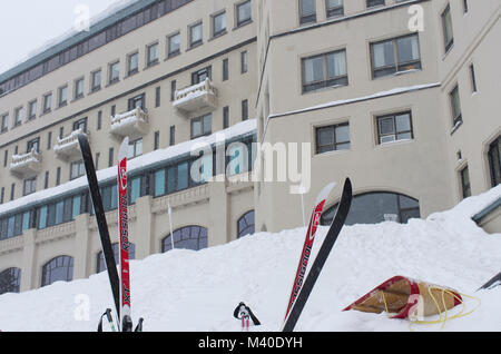 Lake Louise, Alberta, Canada.  The historic Chateau Lake Louise during a January snowfall with skis and a toboggan in the foreground. Stock Photo