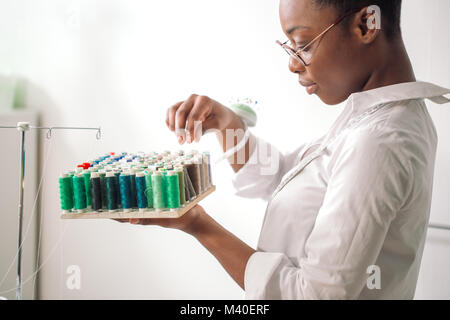 african seamstress holding coils with threads Stock Photo