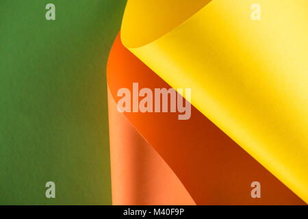 rolled yellow and orange papers on green background Stock Photo