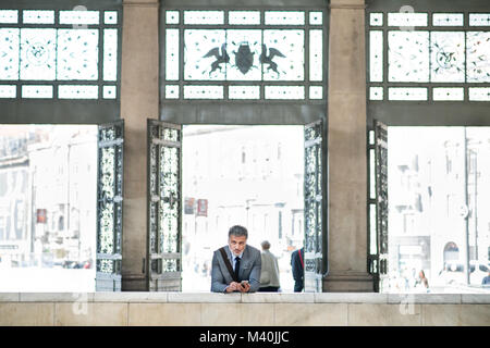 Mature businessman with smartphone on a train station. Stock Photo