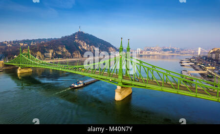 Budapest, Hungary - Aerial panoramic view of beautiful Liberty Bridge (Szabadsag Hid) with barge going on River Danube and Citadella, Statue of Libert Stock Photo