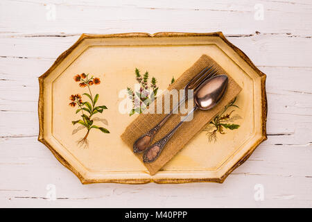 Antique tray with old cutlery spoon and fork  on white wooden background, view from above, flatlay. Stock Photo