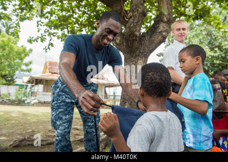 150730-N-PD309-120 ROSEAU, Dominica (July 30, 2015) Information Systems Technician 1st Class Curtis Copeland, a native of LaGrange, Ga., assigned to Naval Computer Telecommunication Center Jacksonville, Fla., presents bags of school supplies to children during a community relations event at Roseau Public Library during Continuing Promise 2015. Continuing Promise is a U.S. Southern Command-sponsored and U.S. Naval Forces Southern Command/U.S. 4th Fleet-conducted deployment to conduct civil-military operations including humanitarian-civil assistance, subject matter expert exchanges, medical, den Stock Photo