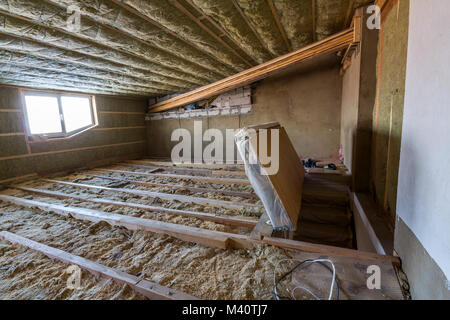 House attic under construction. Mansard walls and ceiling insulation with rock wool. Fiberglass insulation material in wooden frame for cold barrier. Stock Photo