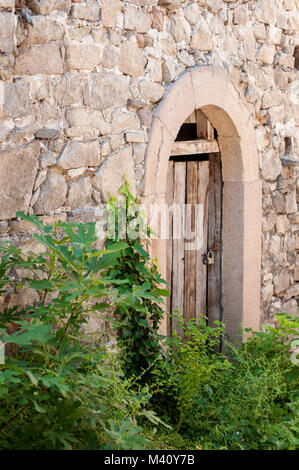 Ancient wooden locked door in stone wall Stock Photo