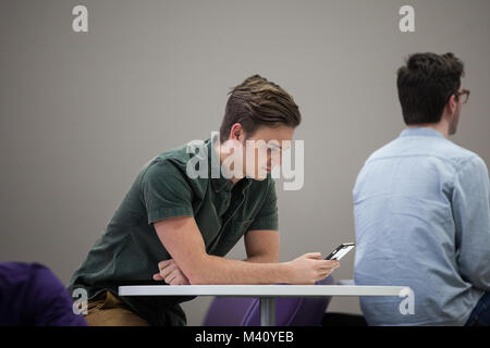 Man using smartphone in waiting area Stock Photo