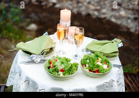 decorated table served for two in rustic, boho style outdoor. Decoration with sackcloth, white fabric and lace, candles and candlesticks. Romantic dat Stock Photo