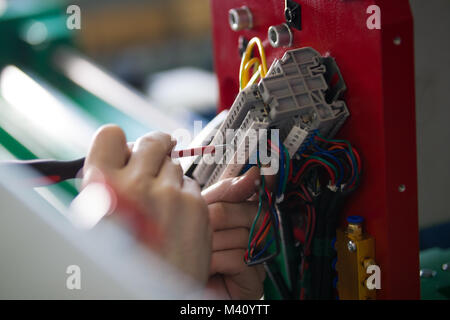 Hands of electrician engineer screwing and testing equipment in fuse box Stock Photo