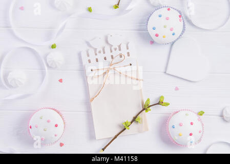 Top view Easter holiday composition of handcraft notebook with empty blank, branch with young shoots of greenery, cupcakes, heart shape on wooden back Stock Photo