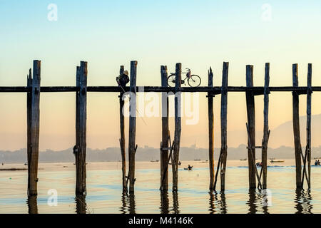 A man is fishing on U Bein Bridge, an old teakwood bridge, spanning over Taungthaman Lake Stock Photo