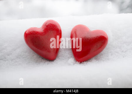 Two red painted wooden hearth shaped figurines on the snow Stock Photo